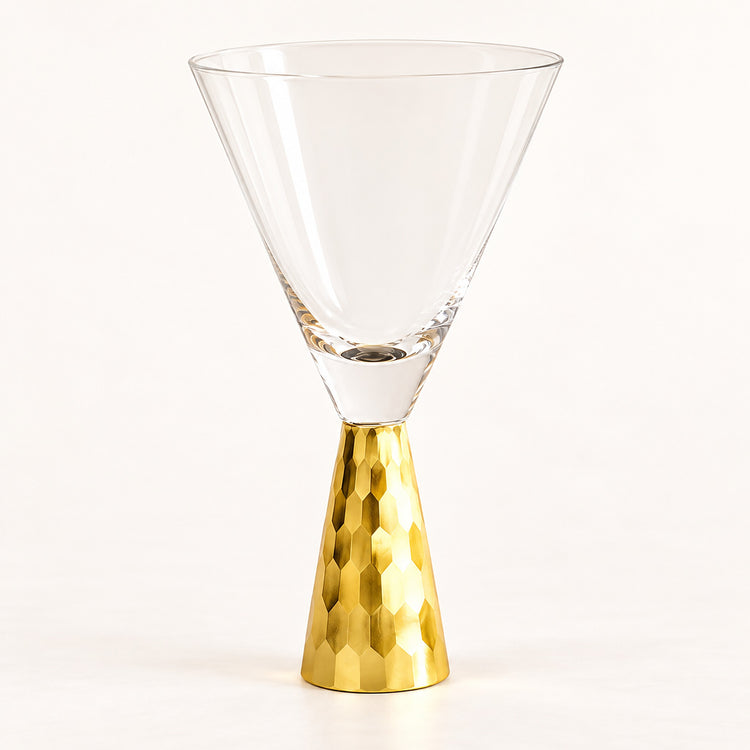 A clear glass martini-style coupe glass with a textured metallic gold base, photographed on a clean white studio background.