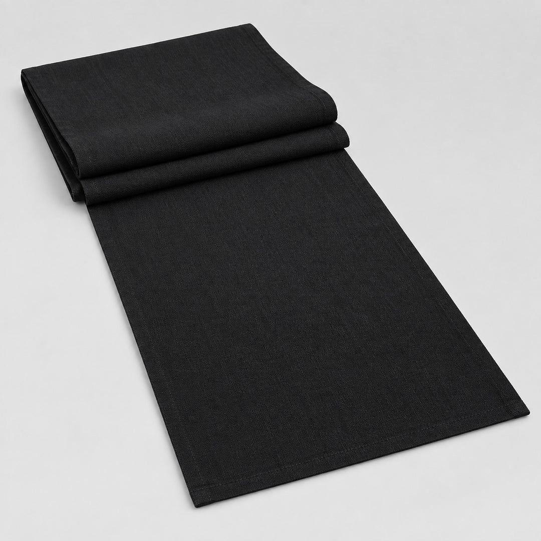 Black cotton table runner with sewn edges, folded studio view; choose length separately.
