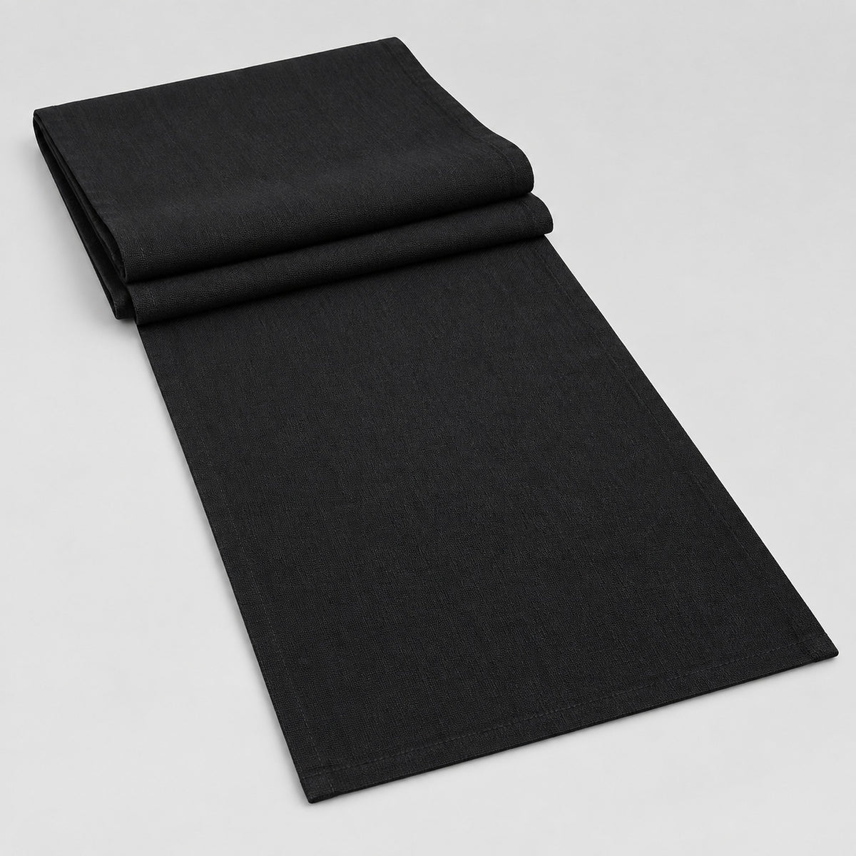 Black cotton table runner with sewn edges, folded studio view; choose length separately.