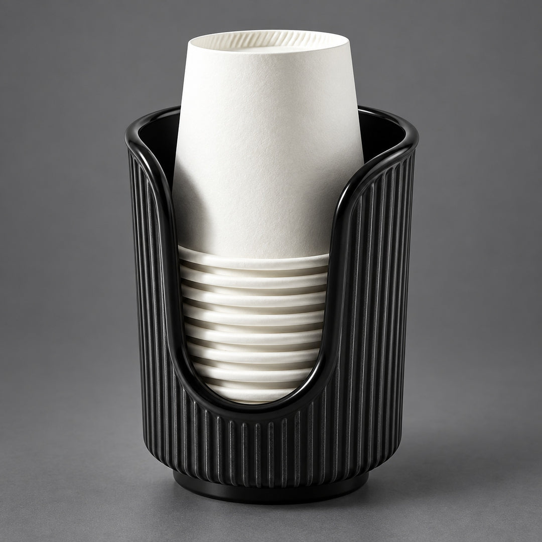 A black ribbed cup holder or cup dispenser holding a stack of white paper cups, photographed on a smooth gray studio background.
