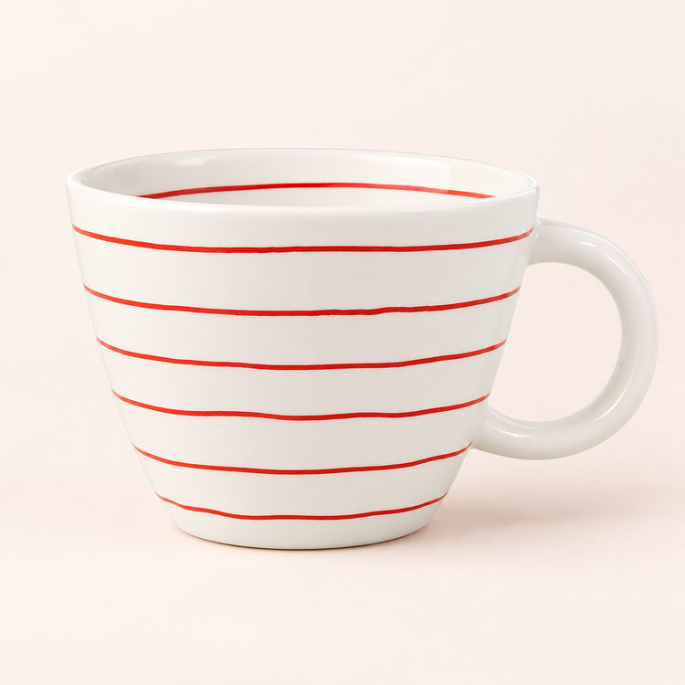 A white ceramic coffee mug with thin, evenly spaced horizontal red stripes, shown against a solid pale pink background.