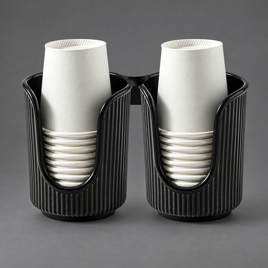 Two black ribbed cup holders, each holding a stack of white paper cups, photographed on a smooth gray studio background.