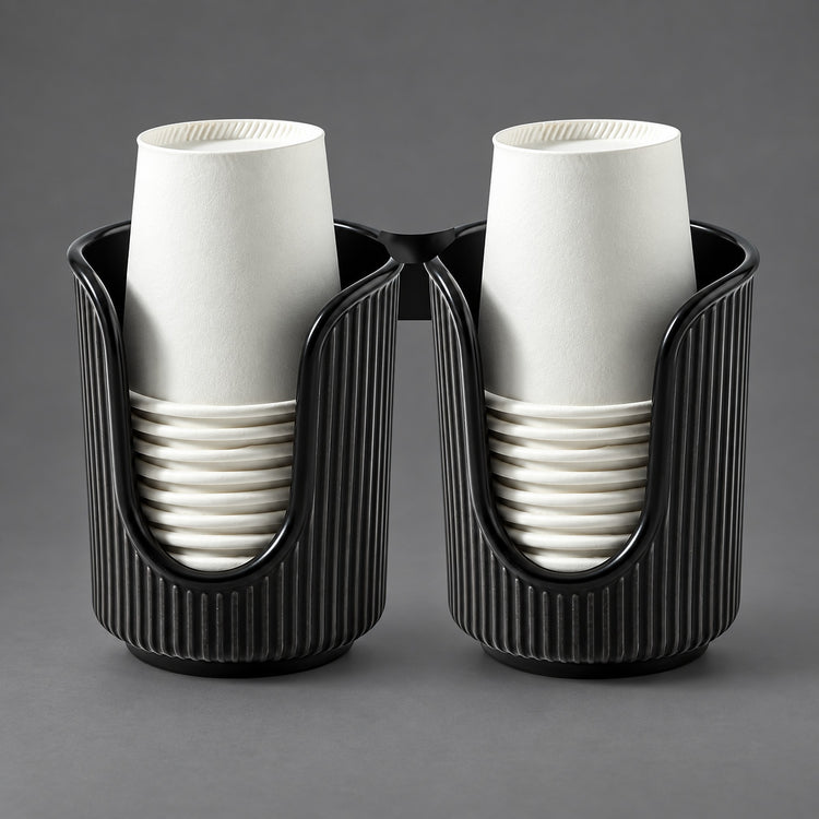 Two black ribbed cup holders, each holding a stack of white paper cups, photographed on a smooth gray studio background.