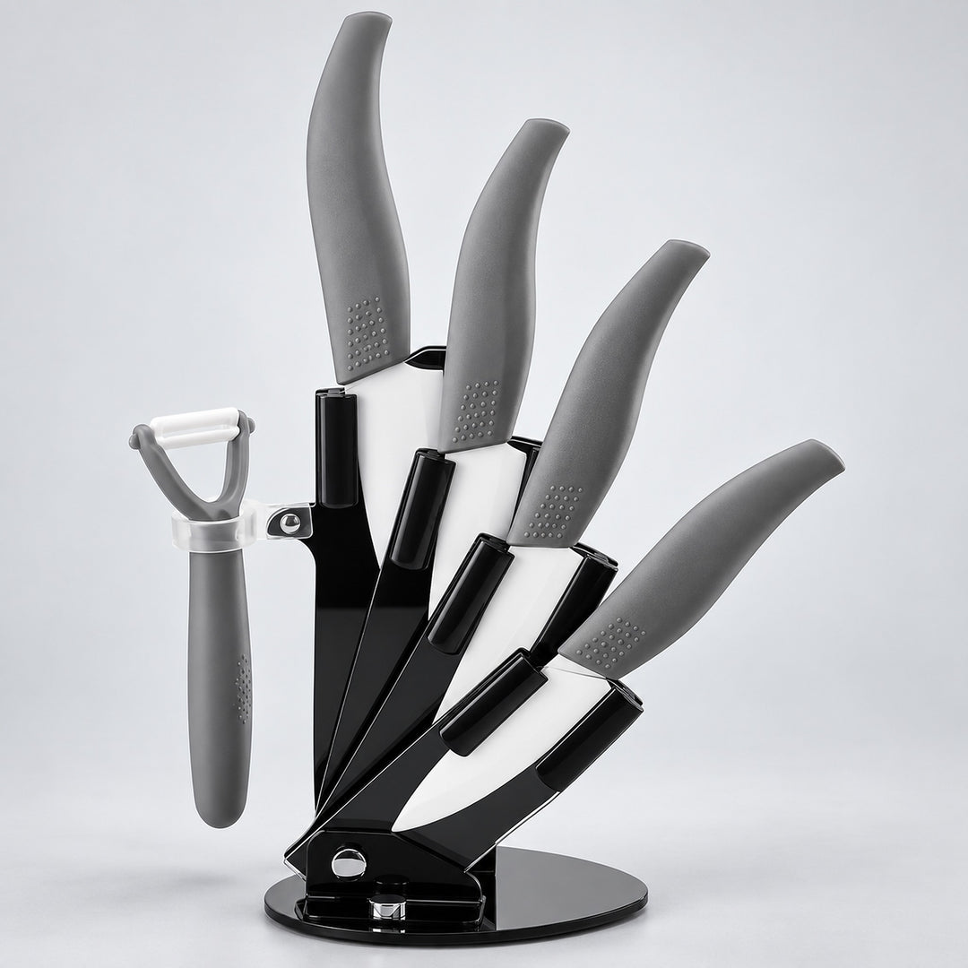 A 5-piece kitchen knife set with gray handles and black blades, displayed on a black magnetic stand with a matching gray peeler to the left, set against a light gray studio background.