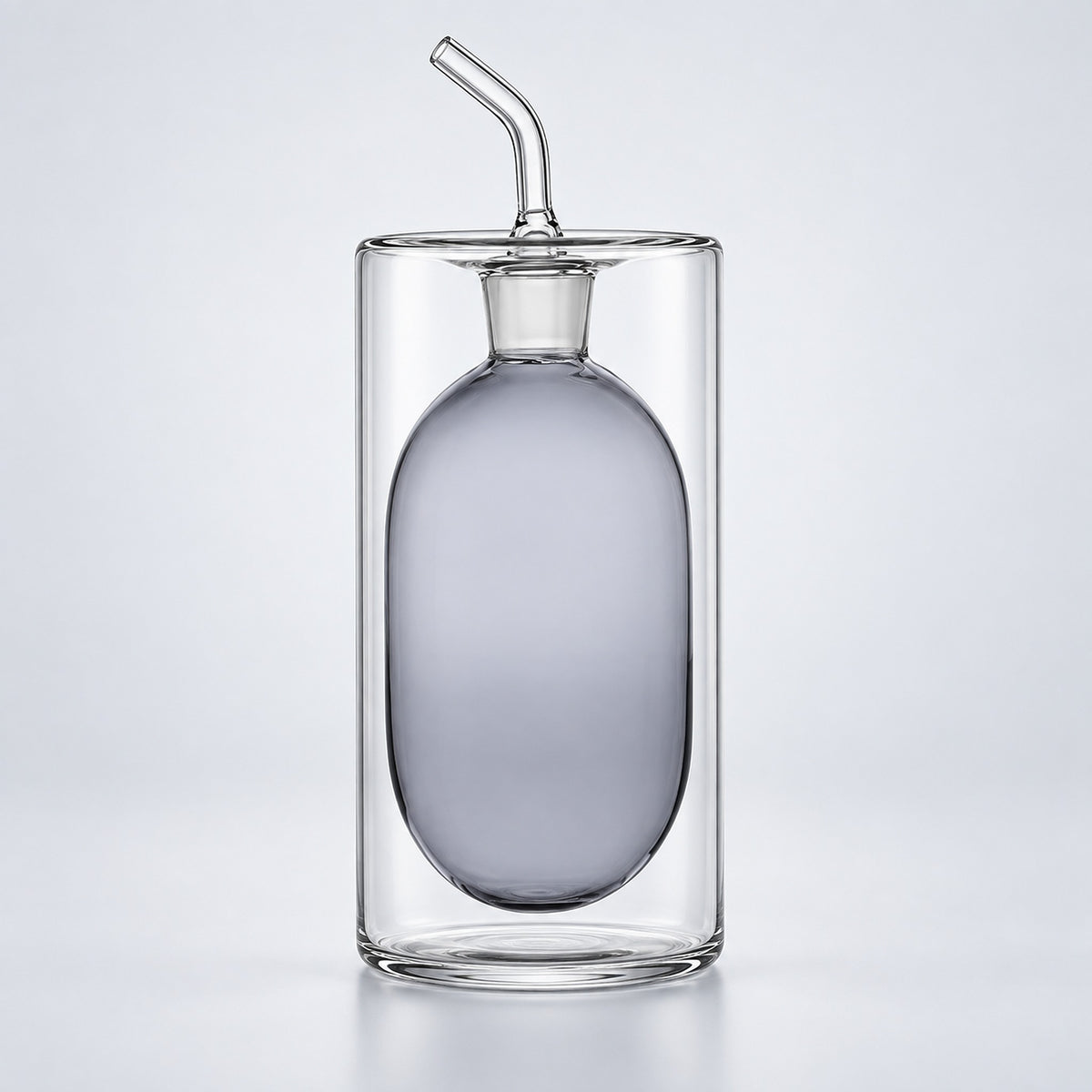 A clear glass double-walled bottle with a frosted oval center and a curved glass straw on a light gray background.