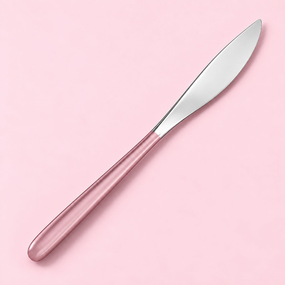 One pink and silver dinner knife on a soft studio background.