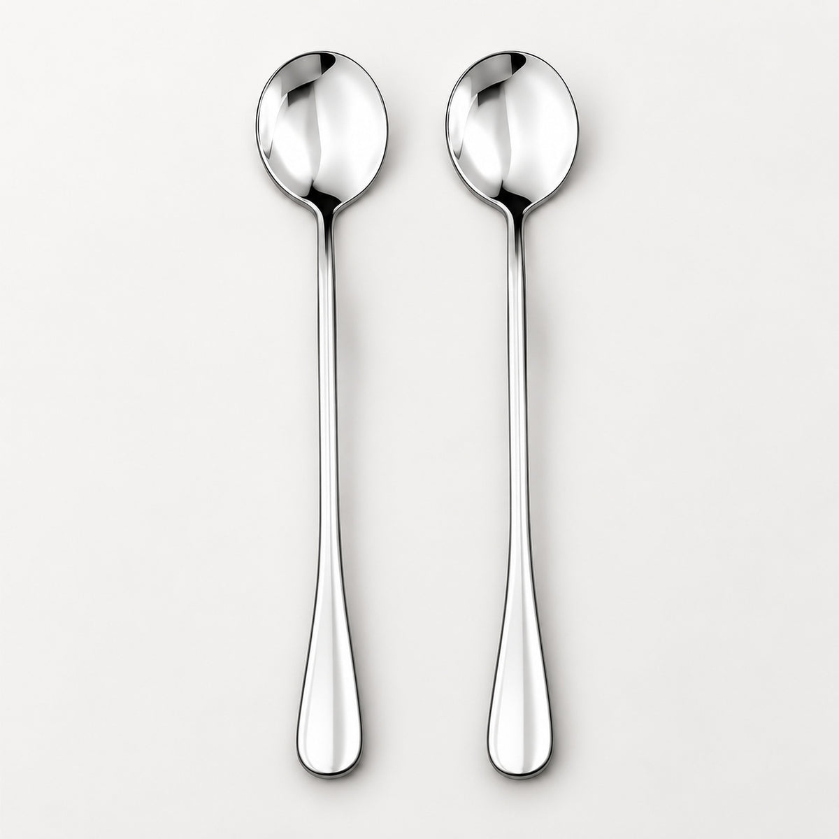 Two polished stainless steel spoons with long handles, shown side by side on a clean, light gray background.