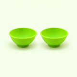 Two light green silicone mini bowls, open tops and pedestal bases.