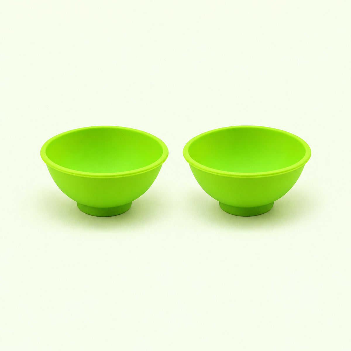 Two light green silicone mini bowls, open tops and pedestal bases.