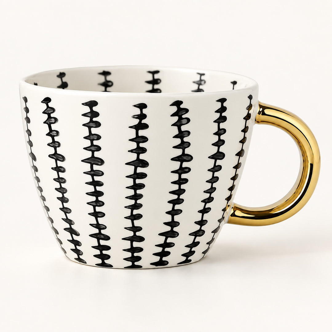 A white ceramic coffee mug with a black vertical dash pattern and a shiny gold handle, shown on a clean white background.