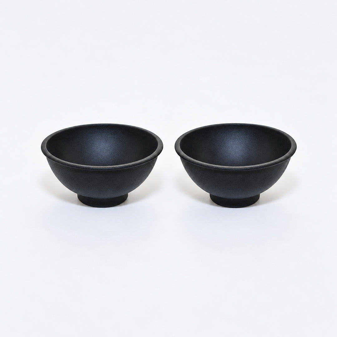Two black silicone mini bowls, open tops and pedestal bases.