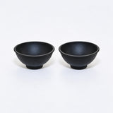 Two black silicone mini bowls, open tops and pedestal bases.