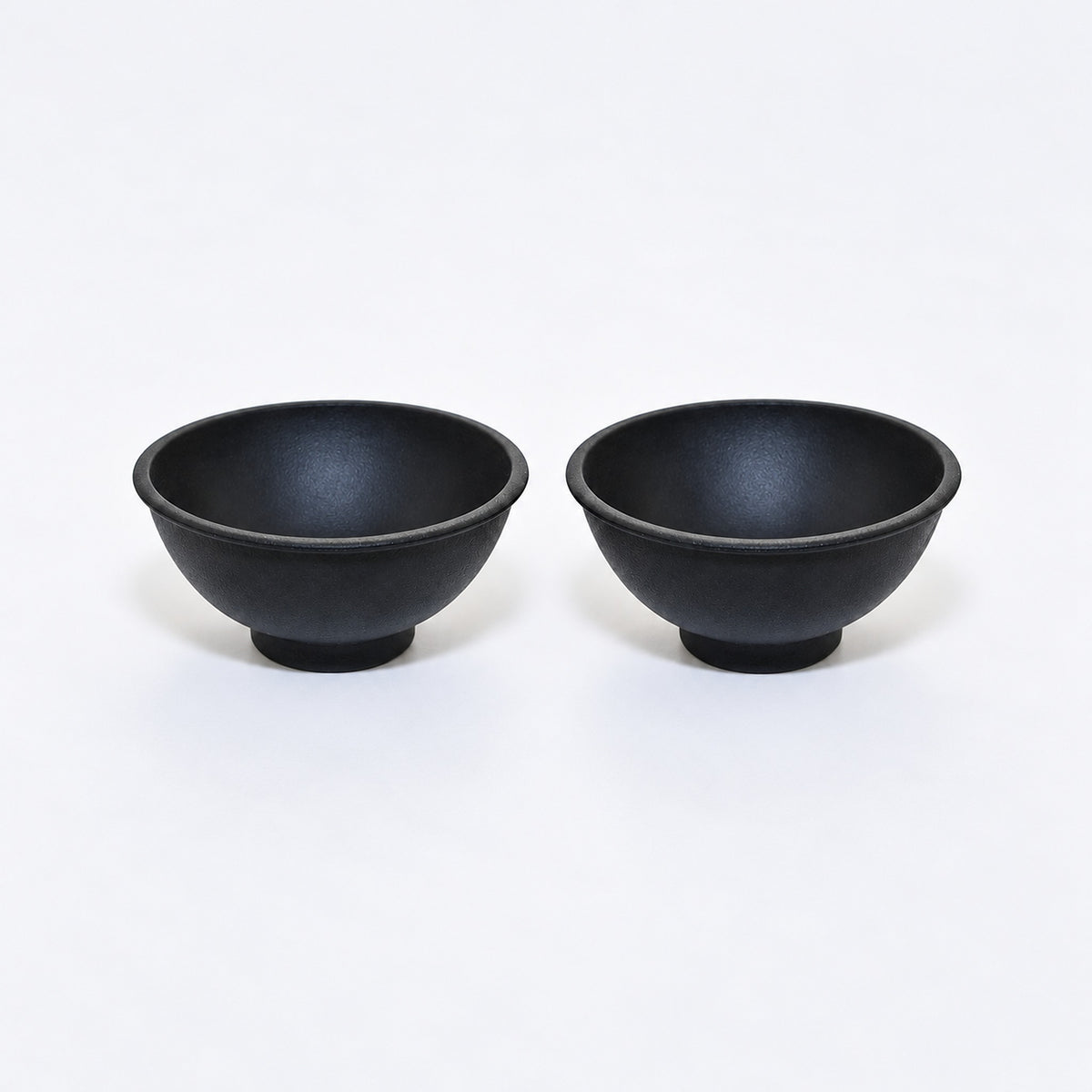 Two black silicone mini bowls, open tops and pedestal bases.