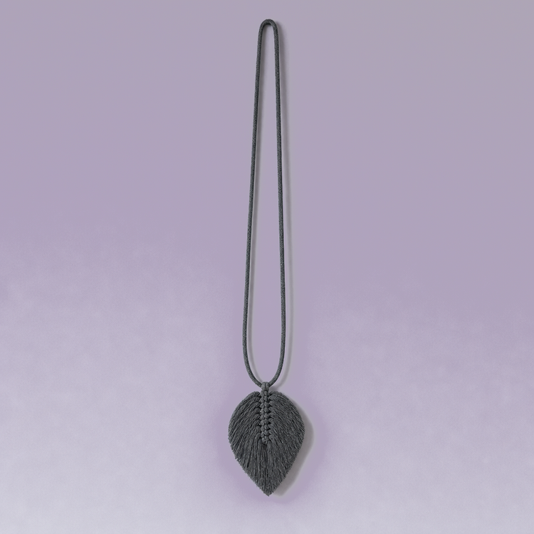 A gray curtain tieback with a leaf-shaped tassel and matching cord, shown tied around the folds of a gray curtain against a light beige background.