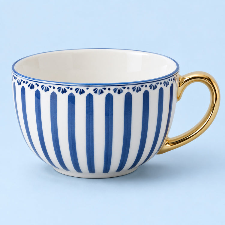 A white ceramic teacup with vertical blue stripes, a blue decorative border, and a shiny gold handle, set against a solid light blue background.