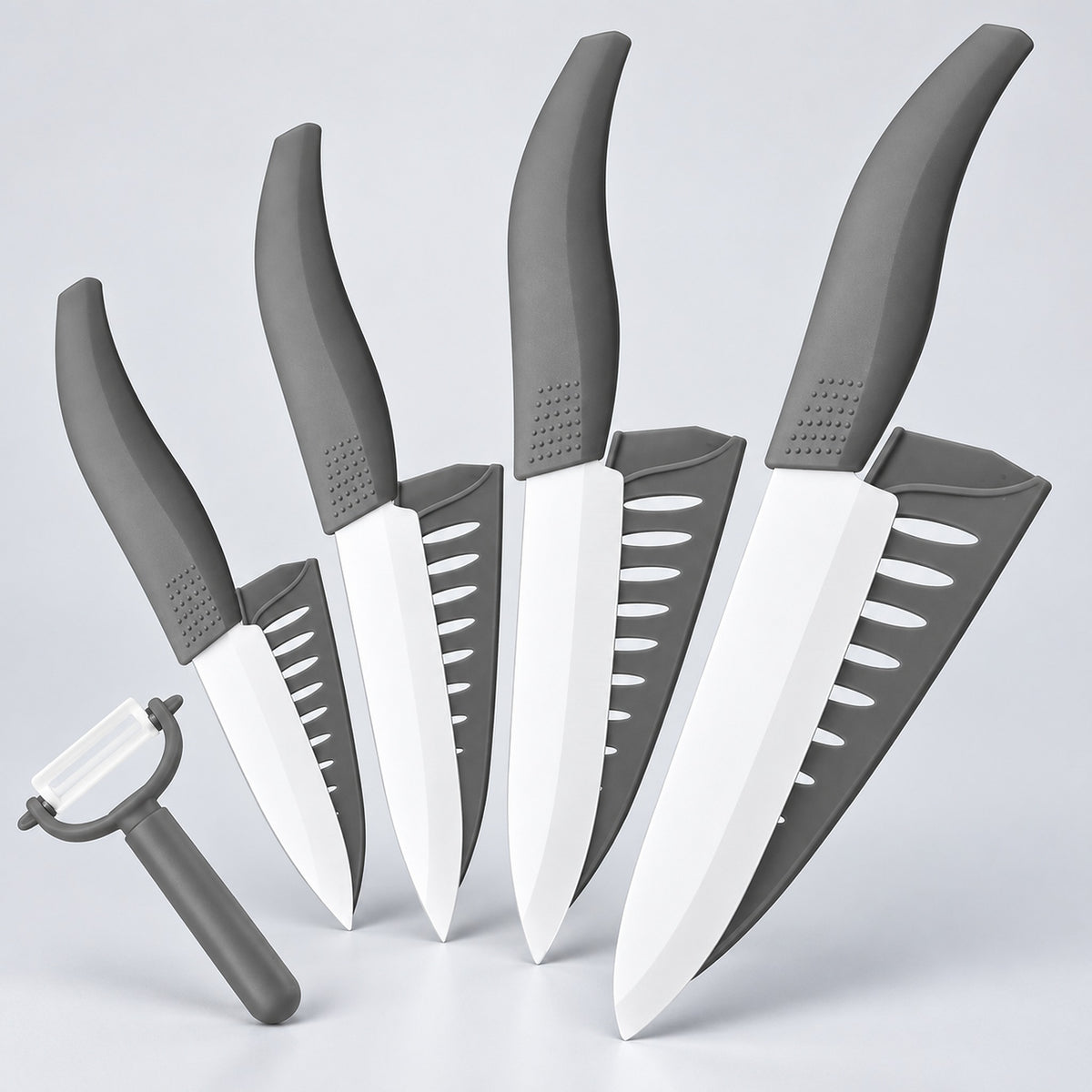 A 5-piece kitchen knife set with white blades and gray handles, arranged diagonally on a light gray background, with a matching gray peeler in the foreground.