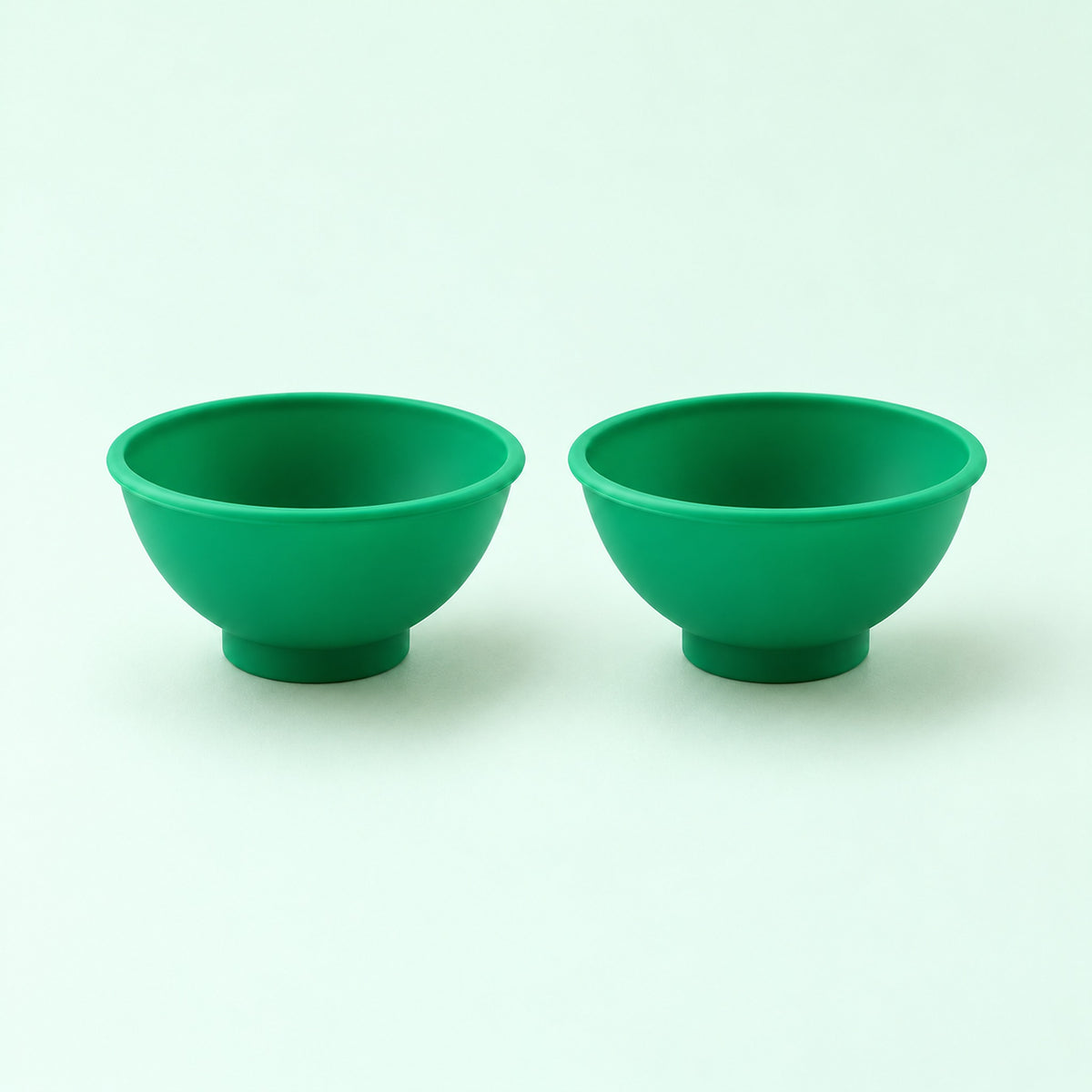 Two dark green silicone mini bowls, open tops and pedestal bases.
