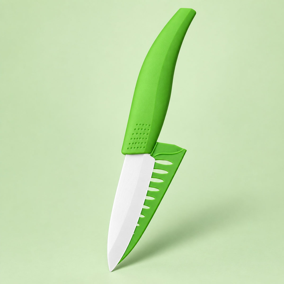 A small green and white plastic knife with a curved ergonomic handle and a serrated cutting edge, shown floating against a solid light green background.