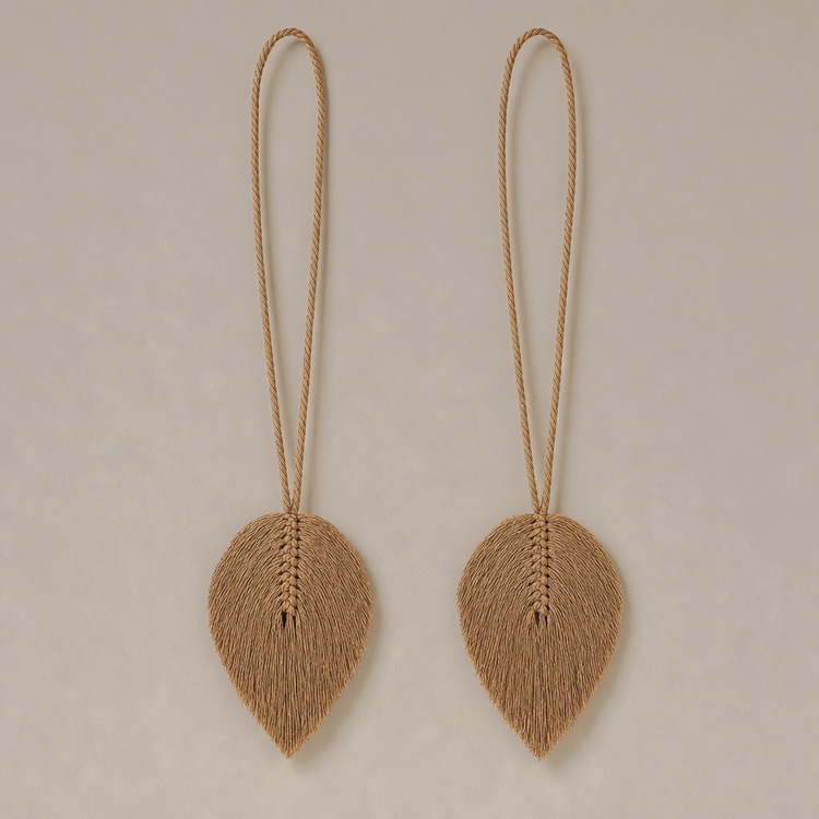 A pair of natural jute leaf-shaped wall hanging ornaments with long hanging loops, displayed against a neutral beige background.