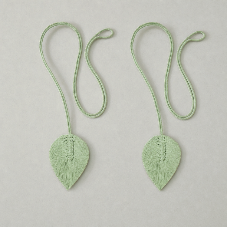 Two matching pale mint green leaf-shaped accessories with long looped cords, arranged side by side on a light gray background.