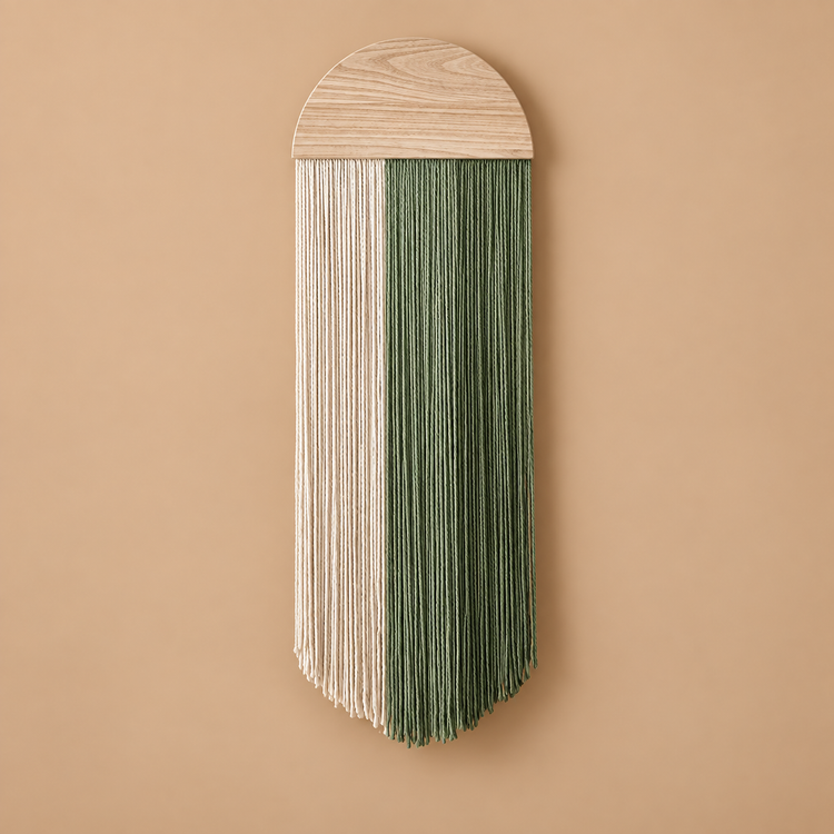 Cream and green fringe under a pale half round wood disc on a warm wall