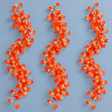 Three artificial maple leaf garland strands hung together on a pale blue wall