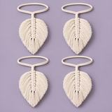 Four cream-colored macrame leaf keychains arranged in a 2x2 grid on a solid lavender background.