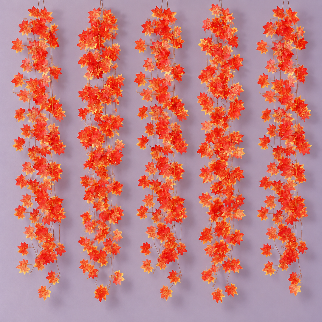 Five red and gold maple leaf vine strands hanging side by side on a lilac wall