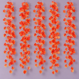 Five red and gold maple leaf vine strands hanging side by side on a lilac wall