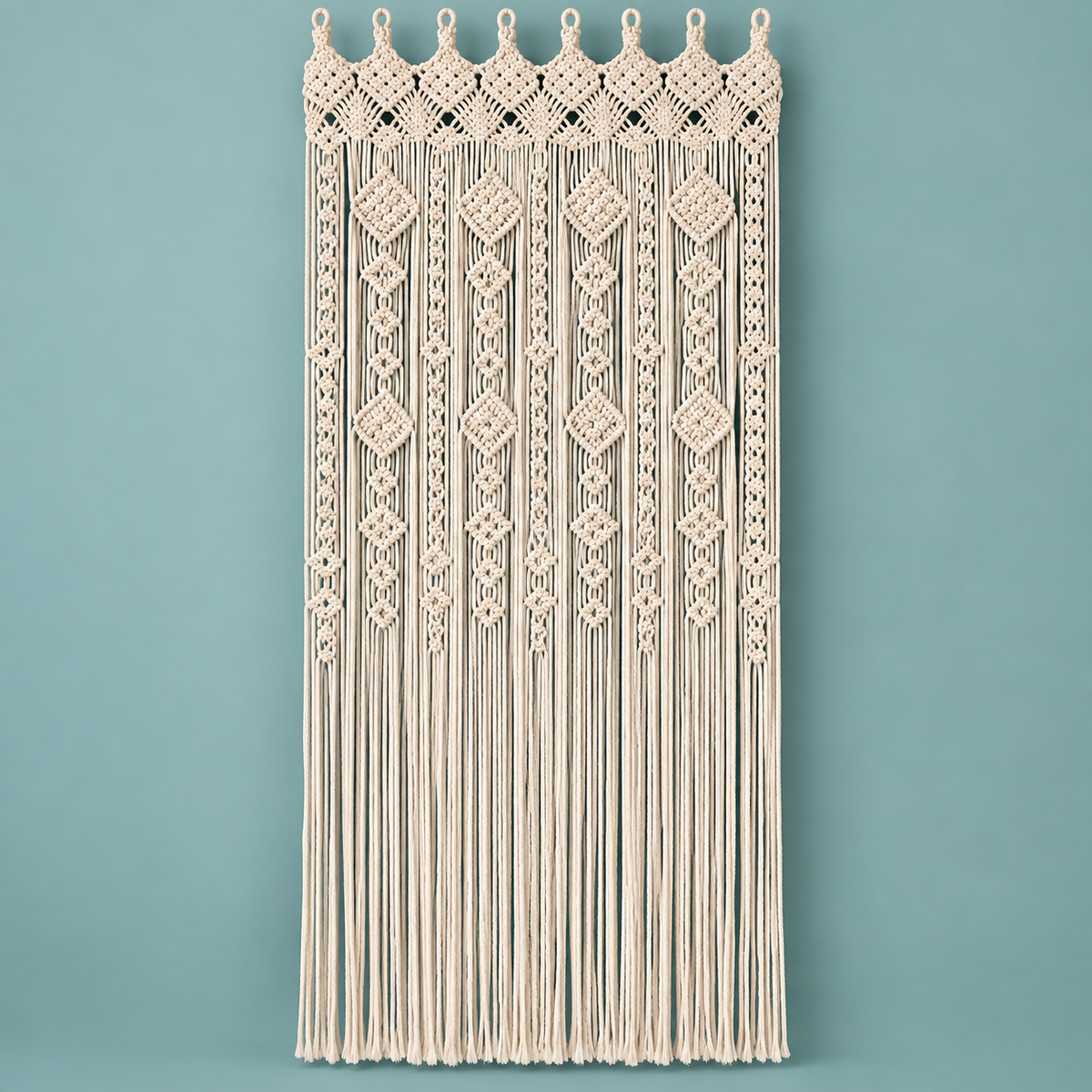 Cream macrame door curtain with a diamond and lattice header on a teal wall