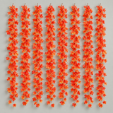 Eight artificial fall leaf garland strands hung together on a pale gray wall