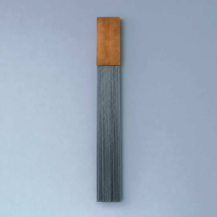 A modern wall-mounted light fixture featuring a rectangular warm brown wood top and a long, pleated gray metal shade below, set against a solid light blue-gray background.