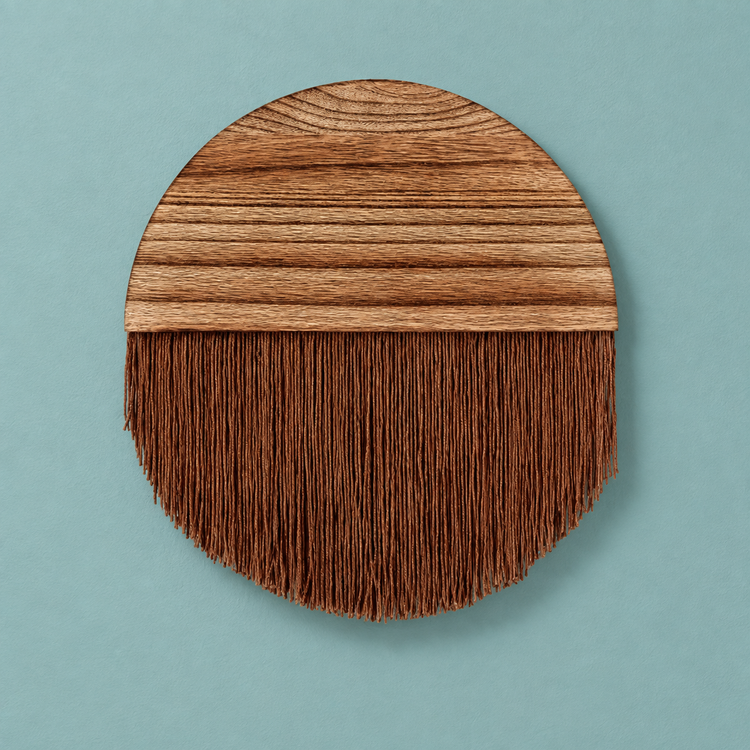 Chestnut brown fringe circle with a figured wood top half on a pale teal wall