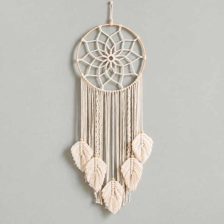 A bohemian-style macrame dreamcatcher with a natural wood hoop, cream-colored woven webbing, and five hanging tassels, shown against a solid light gray background.