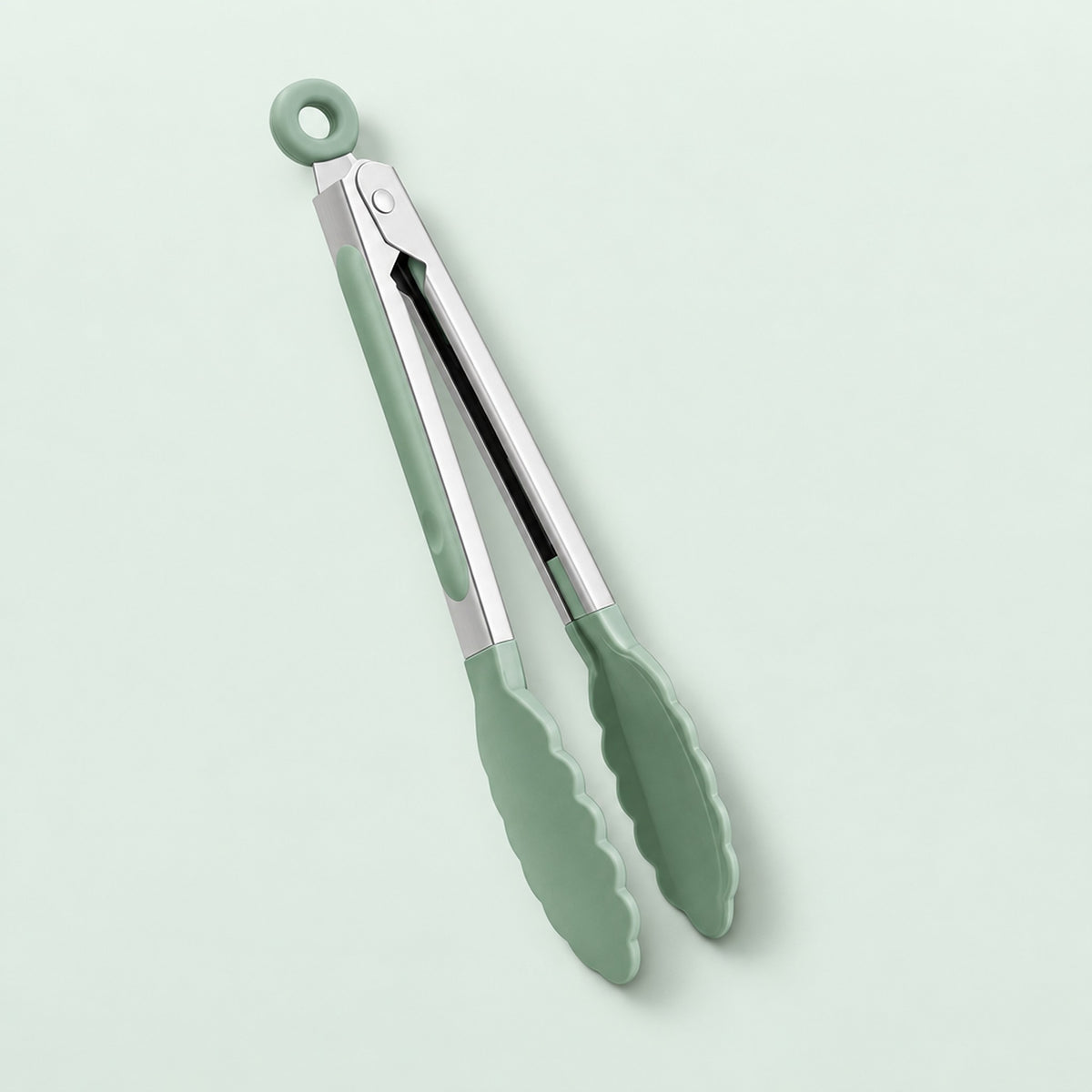 Green silicone-tipped kitchen tongs with a silver metal hinge and a hanging loop, shown on a pale mint green background.