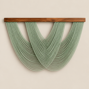 Sage green looping cord swag on a dark batten forming a wide fan on a cream wall