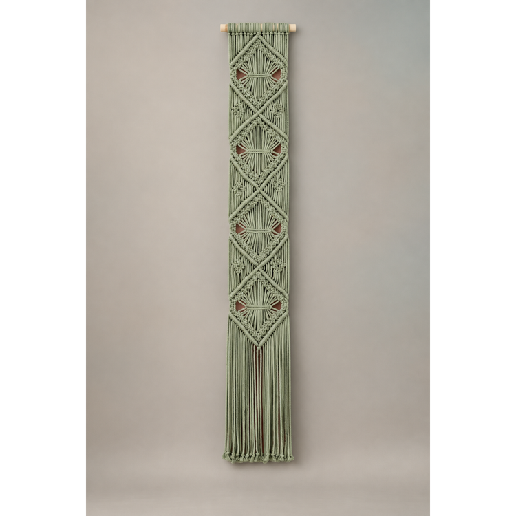 Light sage macrame banner with stacked diamond knotwork on a warm wall