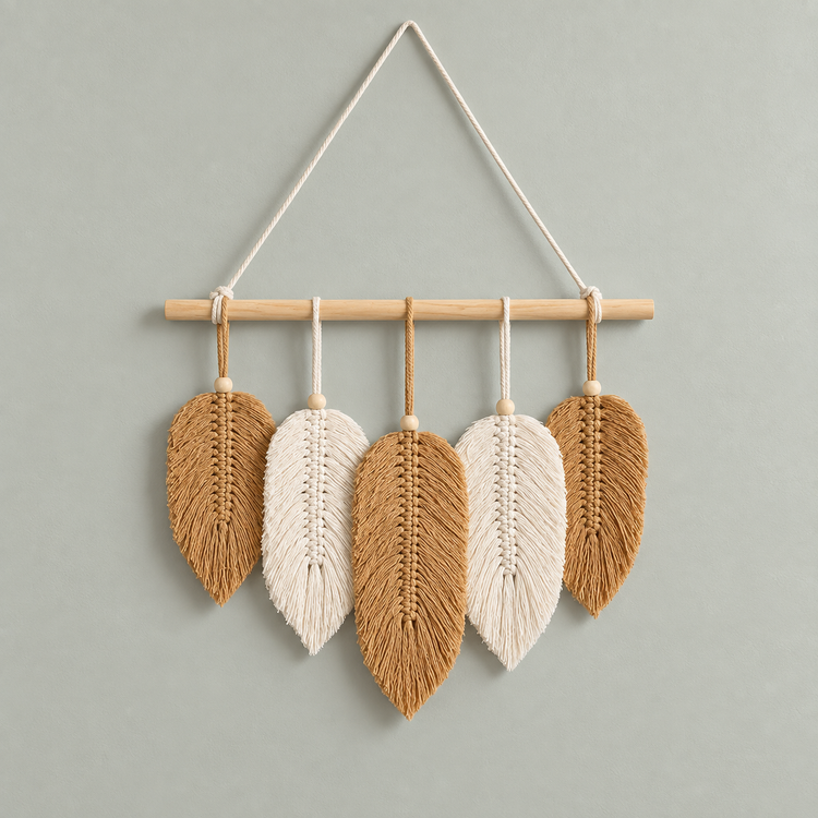 Five tan and cream combed macrame leaves hung from a wooden dowel on a sage wall