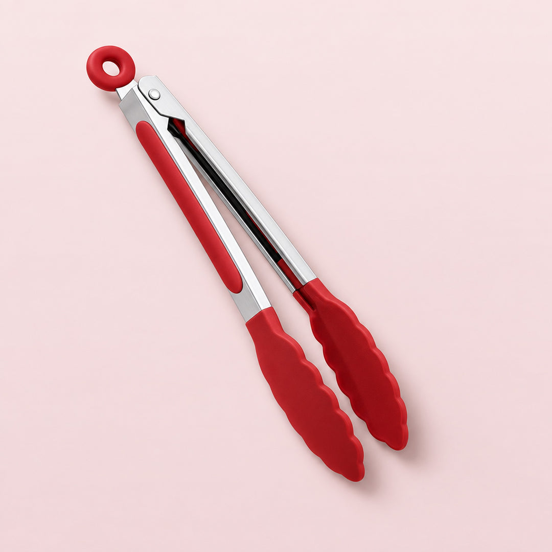 Red silicone-coated tongs with a silver metal hinge and a hanging loop, shown on a solid pale pink background.