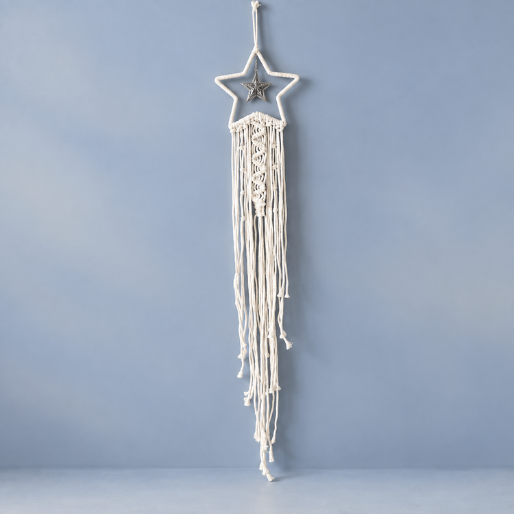 Cream macrame star dream catcher with long cord fringe on a blue background