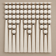 Grid of cream wound yarn spheres with black bindings and long tassels on a warm wall